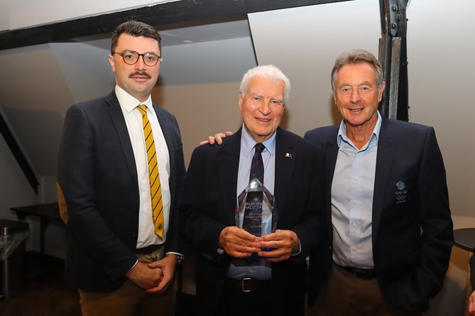 Abergavenny Hockey club president Trevor Scott, centre, and club chairman Luke Rees, left with the commemorative glass presented in honour of Bill Griffiths by Olympic gold medallist Lynn Davies, right 